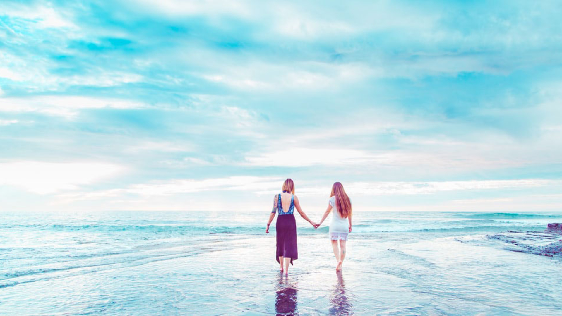 Two women holding hands on the beach